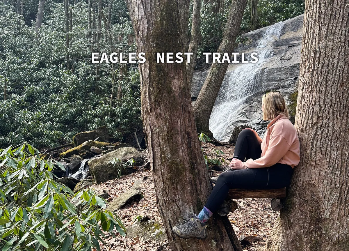A tranquil waterfall set in lush foliage, with a person relaxing nearby. The scene highlights a quiet, beautiful spot for hiking, picnicking, and nature appreciation—ideal for family excursions.